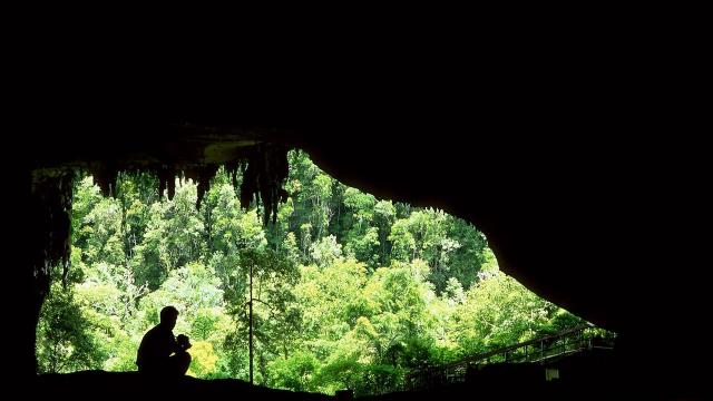 A man sits at the mouth of one of the caverns of Niah Caves in Malaysia.